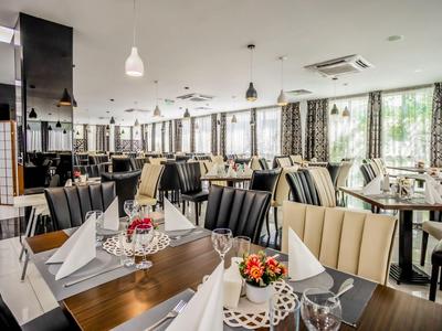 Modernes Restaurant mit eleganten Holztischen, bequemen Stühlen und neutraler Beleuchtung.