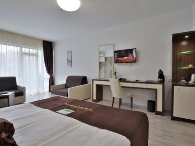 Habitación de hotel moderna con cama, zona de estar y escritorio con silla.