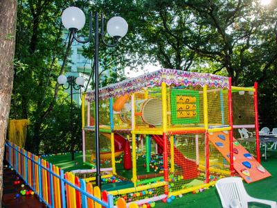 Colorida zona de juegos al aire libre con estructura para trepar y tobogán, rodeada de árboles.