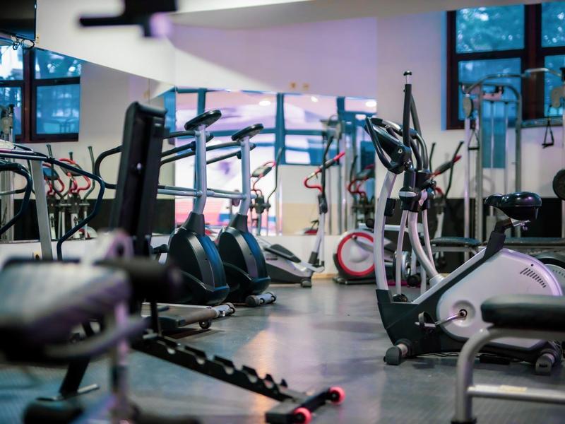 Gimnasio moderno con varios equipos de ejercicio y grandes ventanas.