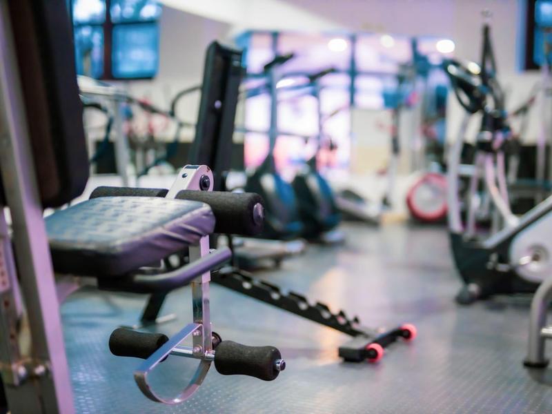 Gimnasio con equipo de ejercicio en primer plano y más máquinas al fondo