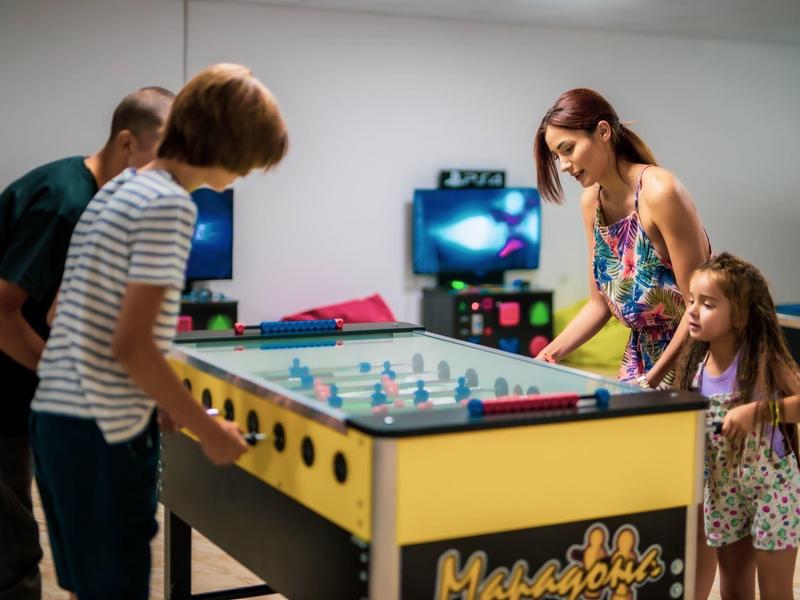 Cuatro personas juegan en una mesa de air hockey en una sala de juegos.