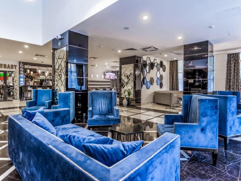 Área de salón de hotel lujosa con sillones de terciopelo azul y diseño moderno.