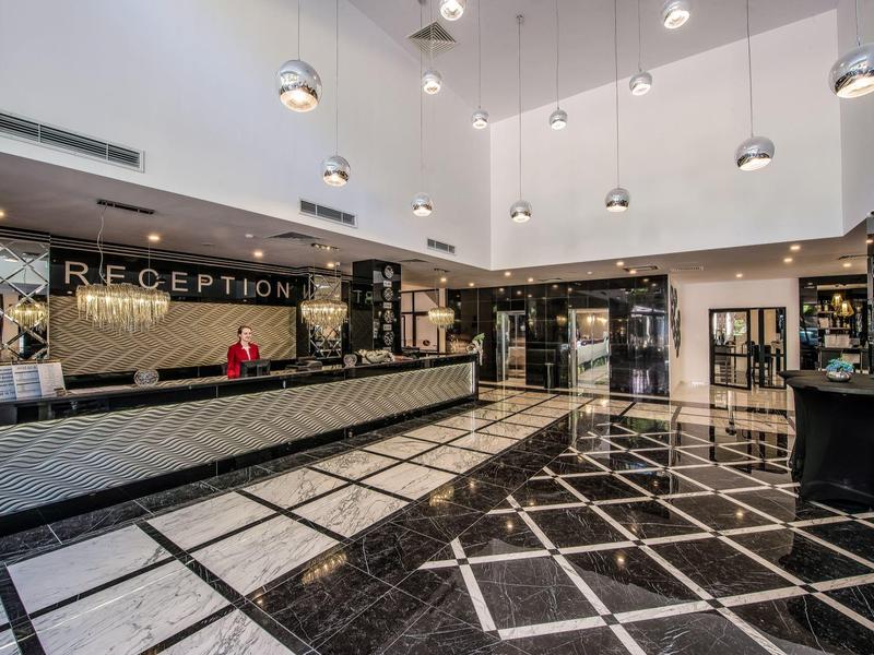 Amplia recepción de hotel con diseño moderno y suelo de mármol blanco y negro.