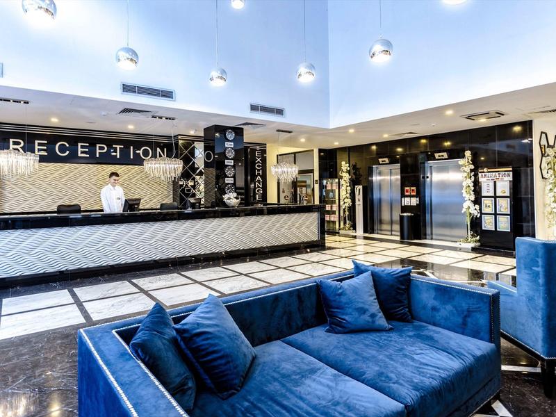 Moderna recepción de hotel con mostrador y asientos azules.