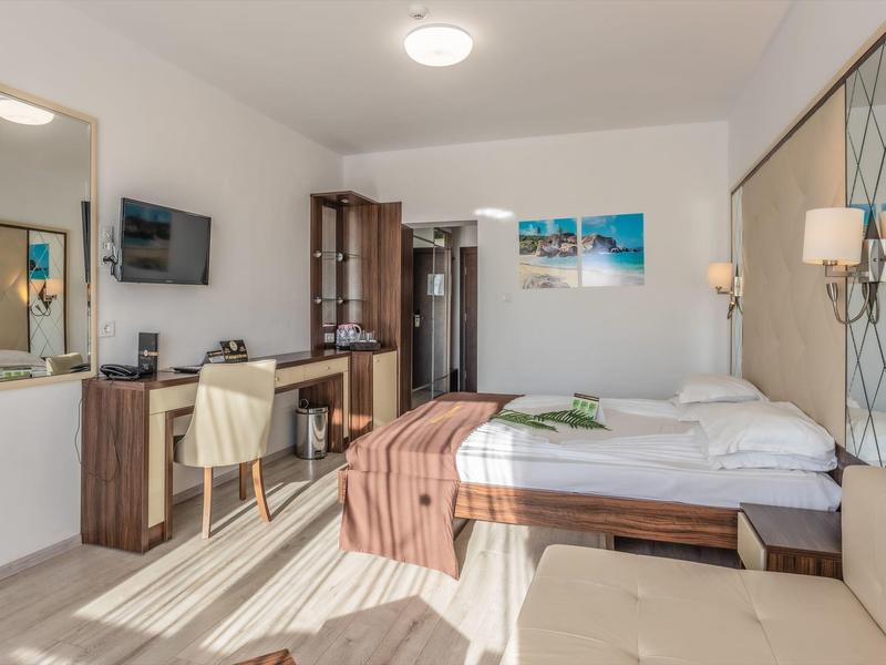 Habitación de hotel luminosa con cama doble, escritorio y mobiliario moderno.