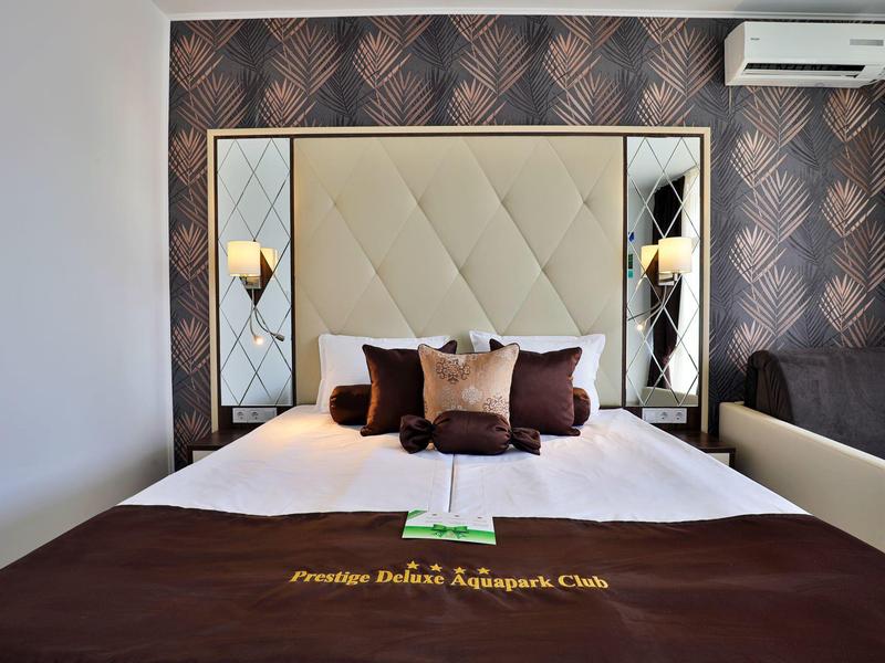 Cama doble en habitación de hotel con cabecero acolchado y cojines decorativos.