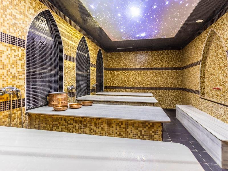 Una habitación de spa de lujo con azulejos de mosaico, chorros de agua masajeadores y un techo oscuro iluminado como un cielo estrellado.