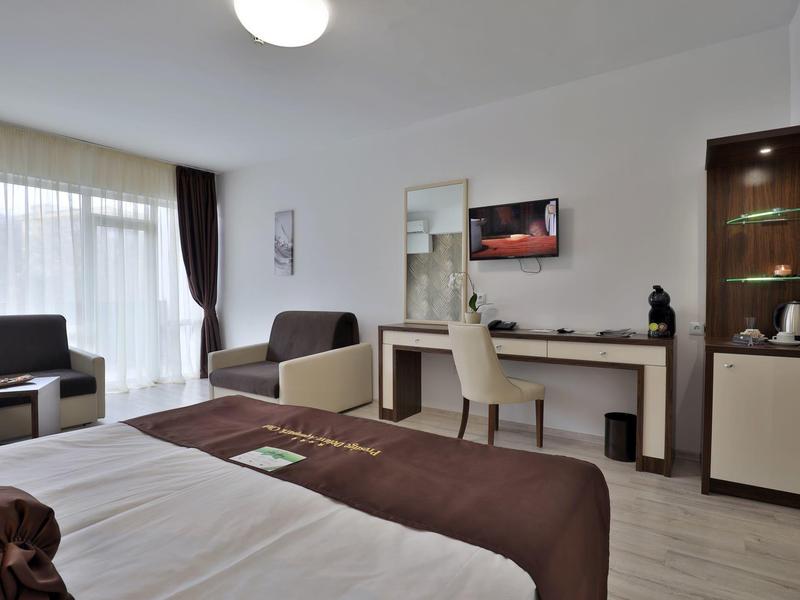 Habitación de hotel moderna con cama, zona de estar y escritorio con silla.