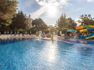 Grande piscine extérieure avec toboggans aquatiques et chaises longues dans un hôtel par une journée ensoleillée.
