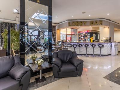 Moderne hotelbar met zwarte leren banken en stijlvolle krukken bij de bar.