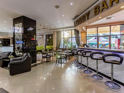 Moderne hotel lobby met bar, zitplaatsen en grote ramen.