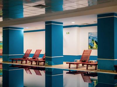 Binnenzwembad met blauwe zuilen en rode ligstoelen in een hotel