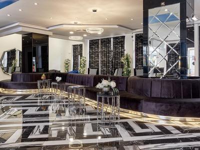 Moderne hotel lobby met zwarte fluwelen bank en glanzende marmeren vloer.