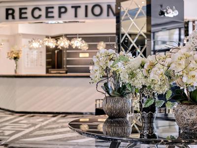 Hotelreceptie met elegante balie en decoratieve witte bloemstukken.