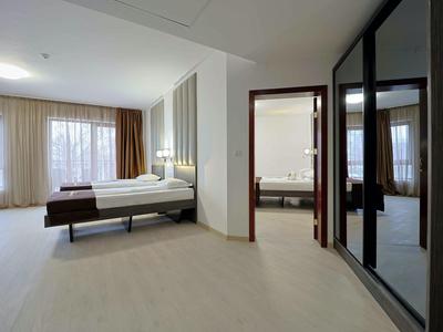 Moderne hotelkamer met groot bed, lichte inrichting en grote spiegelkast.
