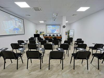 Moderne vergaderruimte met veel stoelen en twee schermen voor presentaties.