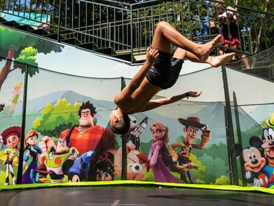 Een jongen springt op een trampoline omringd door kleurrijke muurschilderingen van cartoonfiguren.
