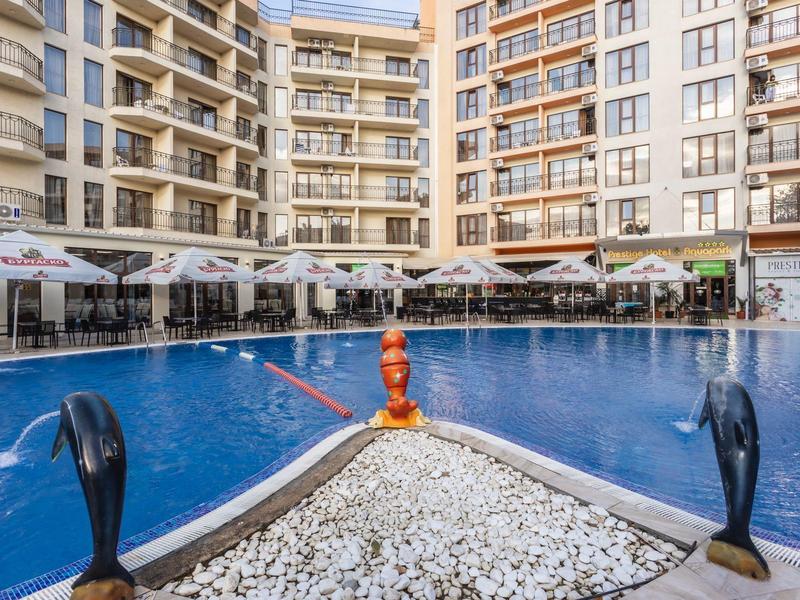 Modern hotelzwembad met parasols en ligstoelen in een binnenplaats.