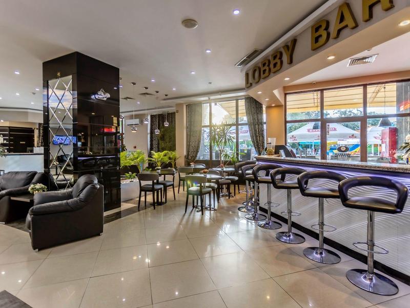 Moderne hotel lobby met bar, zitplaatsen en grote ramen.