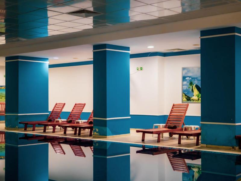 Binnenzwembad met blauwe zuilen en rode ligstoelen in een hotel