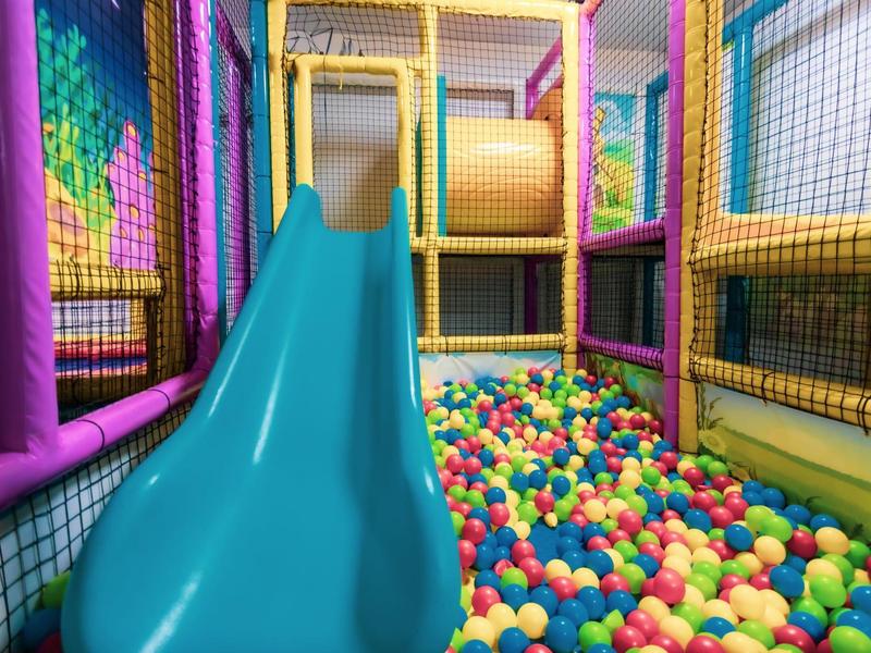 Kleurrijke speelruimte met glijbaan en ballen in een hotel kindergedeelte.