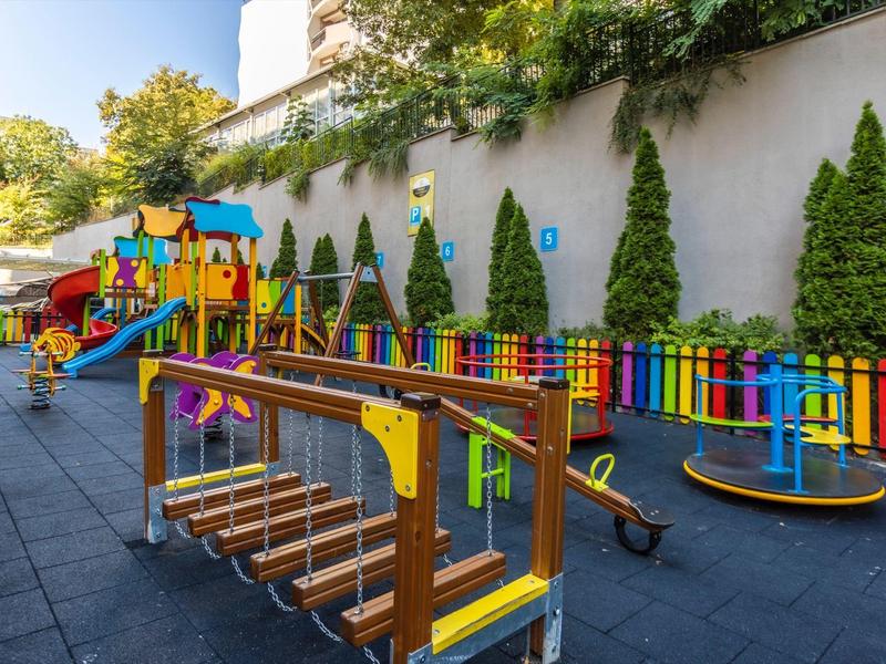 Kleurrijke kinderspeelplaats met klimrek, glijbaan en schommels in een buitenruimte.