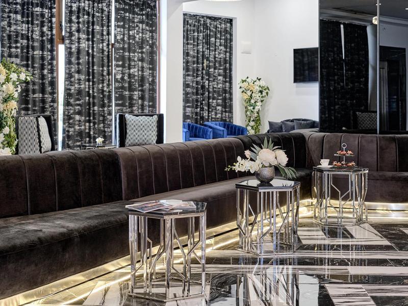 Elegante hotellounge met fluwelen banken, glazen tafels en moderne inrichting.