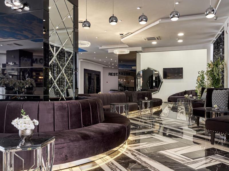 Elegante hotel lounge met moderne meubels, marmeren vloer en stijlvolle verlichting.