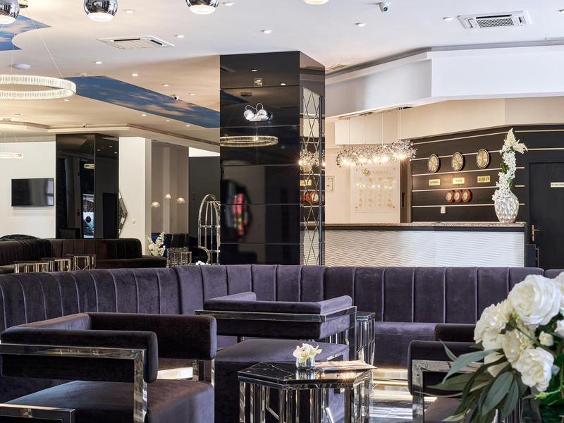 Moderne hotellobby met een donkere fluwelen bank, glazen en metalen tafels en bloemenarrangement.