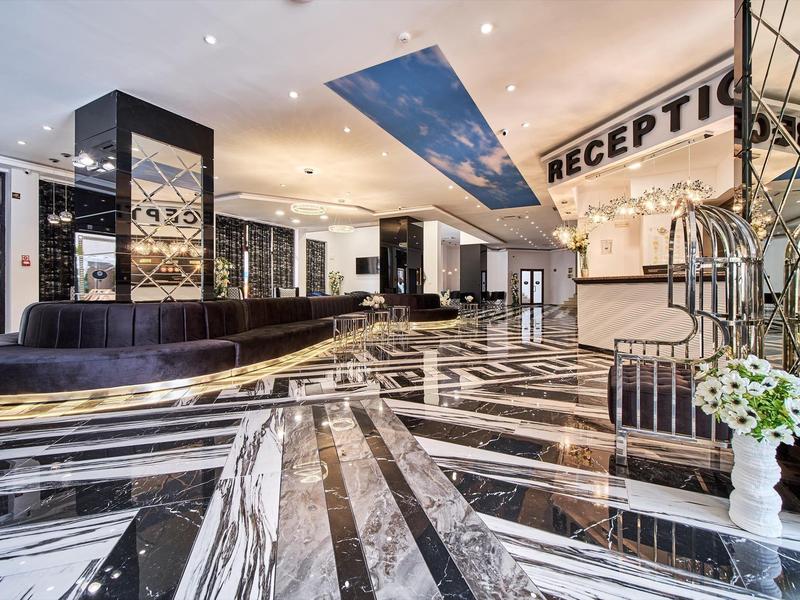 Moderne hotellobby met glanzende zwart-witte marmeren vloer en stijlvolle receptiebalie.