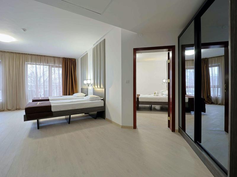 Moderne hotelkamer met groot bed, lichte inrichting en grote spiegelkast.