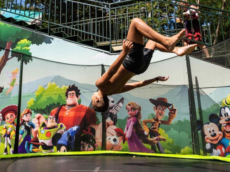Een jongen springt op een trampoline omringd door kleurrijke muurschilderingen van cartoonfiguren.