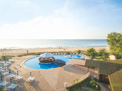 Hotel pool area with two round pools, sun umbrellas, and a view of the beach and sea
