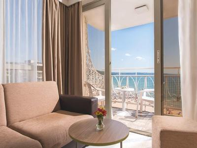 Gezellige hotelkamer met balkon, zeezicht en comfortabele zitplaatsen.