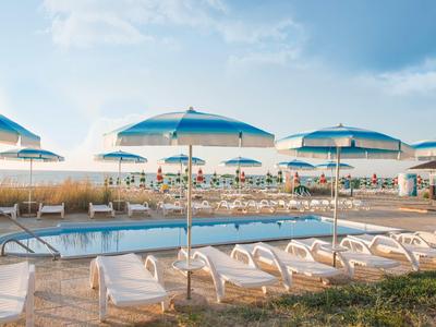 Pool area with sun loungers and blue umbrellas at a sunny beach hotel