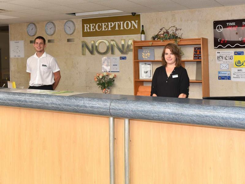 Twee receptiemedewerkers staan achter een hotelreceptiebalie.