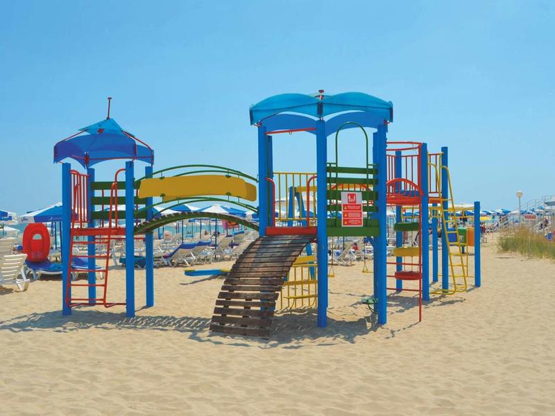 Kleurrijke kinderspeelplaats op zandstrand onder heldere hemel