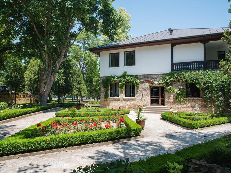 Gemütliches Hotelgebäude in einem Garten mit Wegen und gepflegten Blumenbeeten.