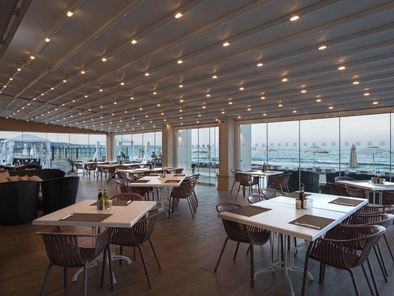 Elegantes Restaurant mit großen Fenstern und Blick auf die Stadt bei Sonnenuntergang.