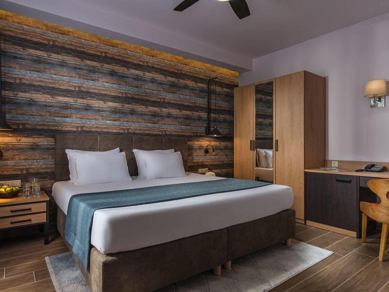 Gemütliches Hotelzimmer mit Doppelbett, Holzvertäfelung und Schreibtisch am Fenster.