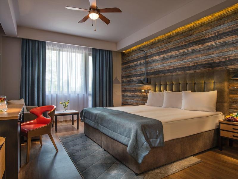 Gemütliches Hotelzimmer mit Doppelbett, rustikaler Holzwand und modernem Dekor.