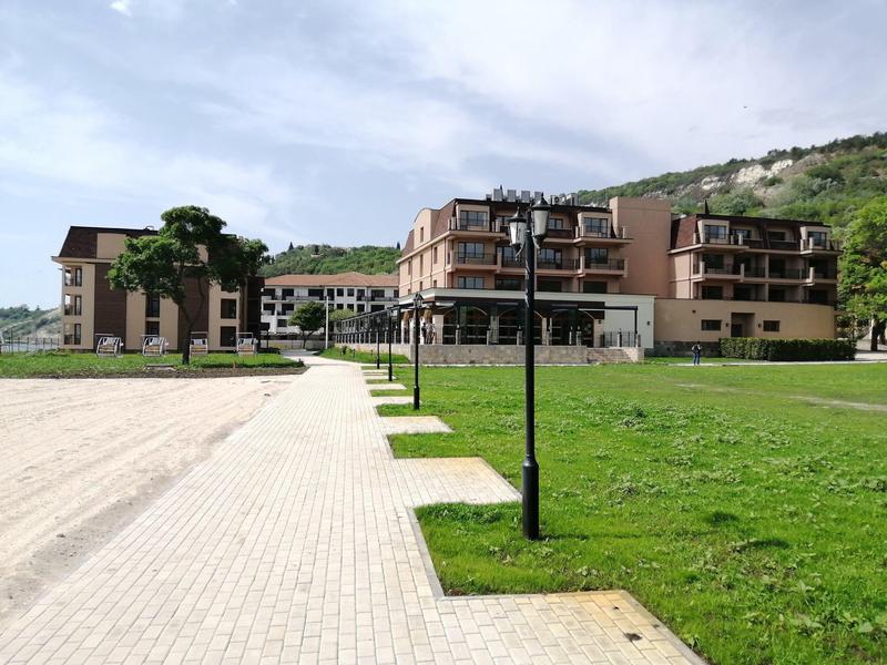 Modernes Hotelgebäude in einer grünen Landschaft mit Weg und Berg im Hintergrund.