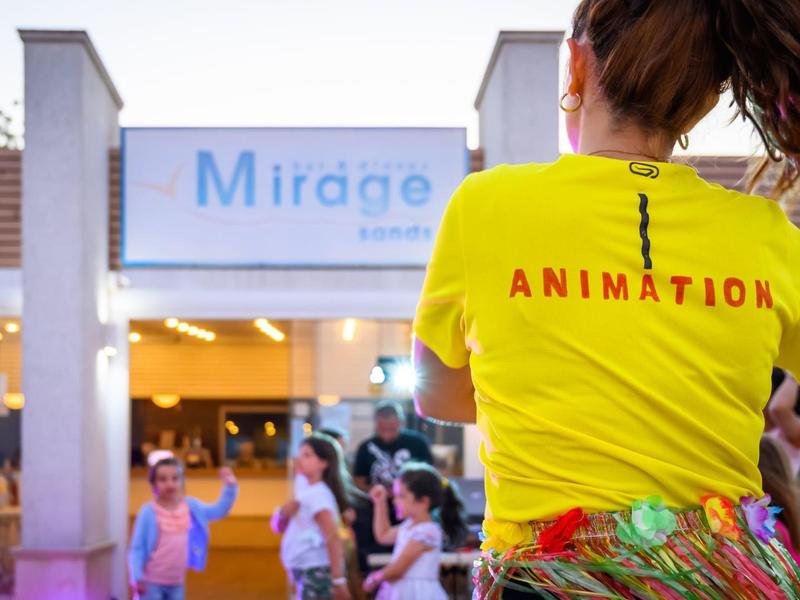 Person in gelbem T-Shirt mit Animationstext begrüßt Gäste vor einem Hotel
