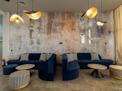 Nowoczesny salon z niebieskimi sofami, wiszącymi lampami i rustykalną ścianą w tle