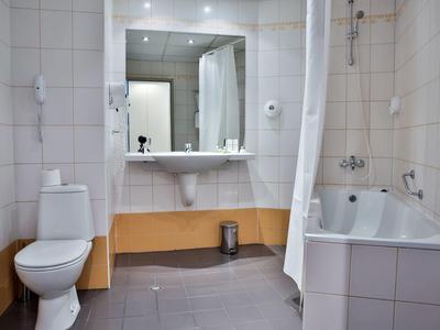Moderne badkamer met toilet, wastafel, grote spiegel, bad en douche.