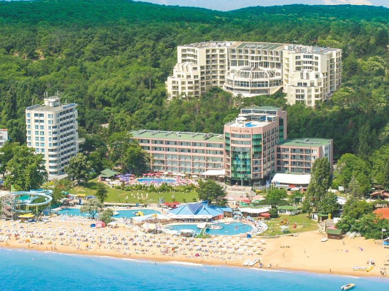 Meerdere hotels aan het strand met een beboste heuvel op de achtergrond.