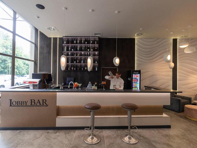 Moderne hotelbar met twee barkrukken en groot raam met uitzicht naar buiten.