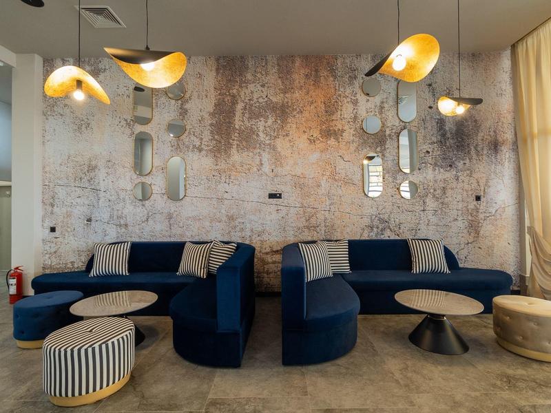 Modern loungegebied met blauwe banken, ronde tafels en bijzondere plafondlampen.