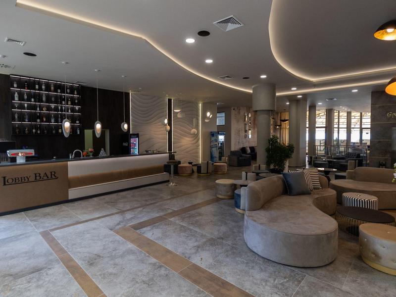 Moderne hotellobby met ronde zithoek en verlichte receptiebalie.